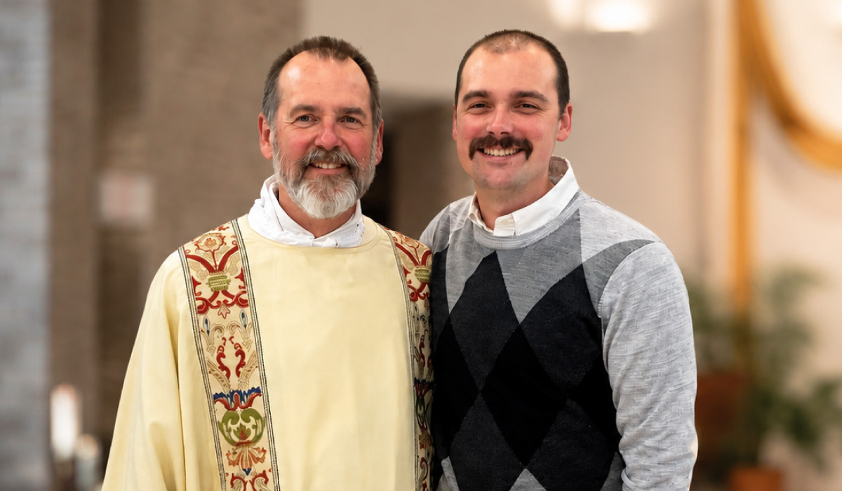 Gabriel Maday standing with a priest
